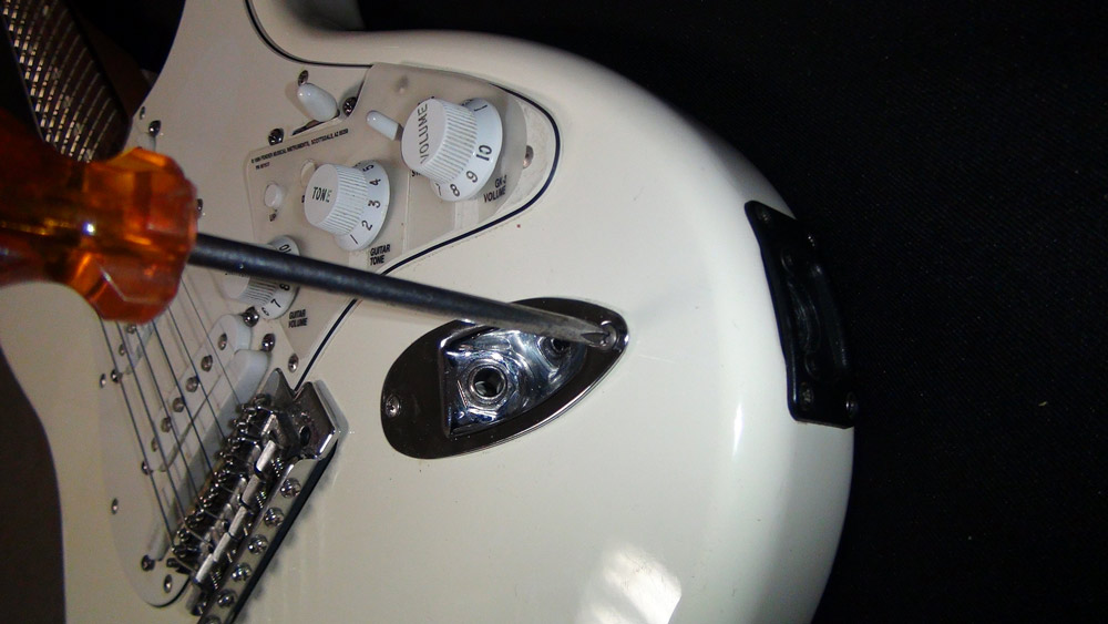 Tighten the screws that hold the plate to the guitar.