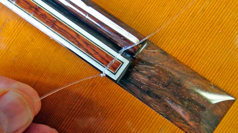 Pull Both Ends of the First String to Tighten the Knot At the Bridge