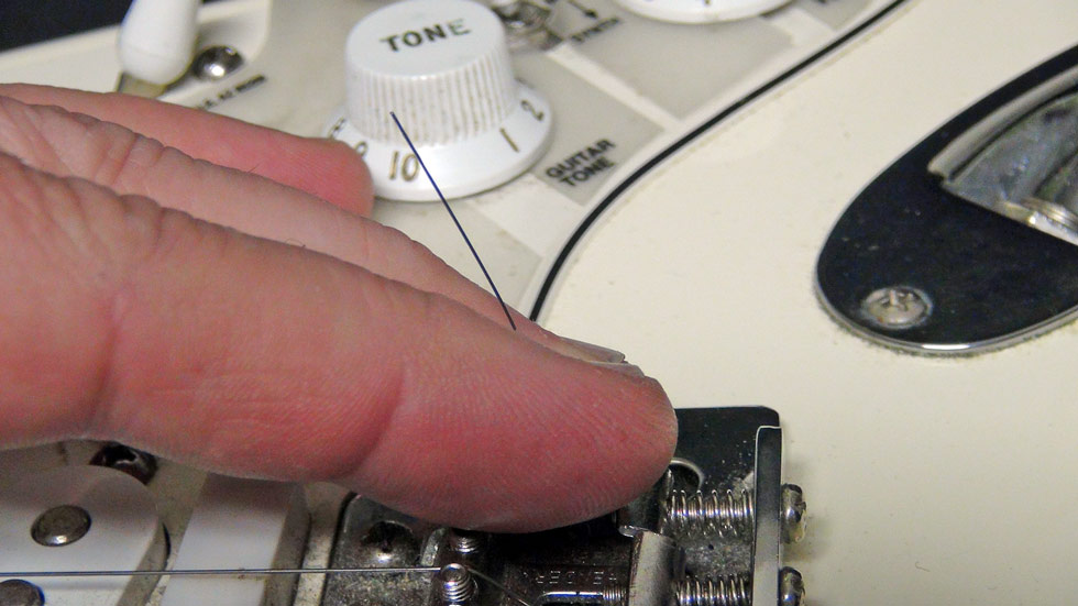 Pull the string through the bridge at the front of the guitar